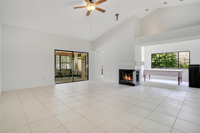 unfurnished living room featuring ceiling fan, light tile patterned flooring, high vaulted ceiling, and a tiled fireplace