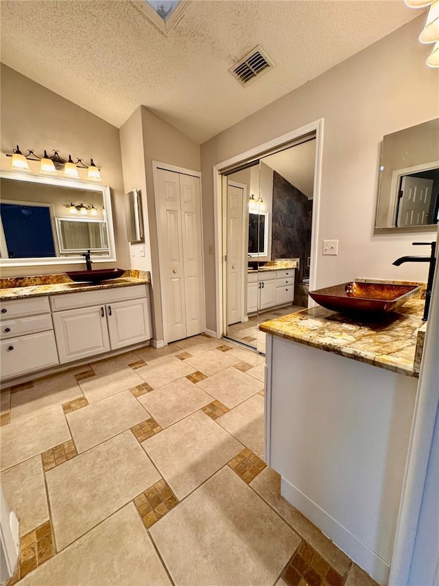 bathroom featuring vanity, lofted ceiling, and a textured ceiling