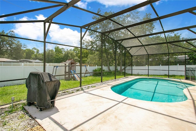 view of pool with area for grilling, a patio area, a playground, and glass enclosure