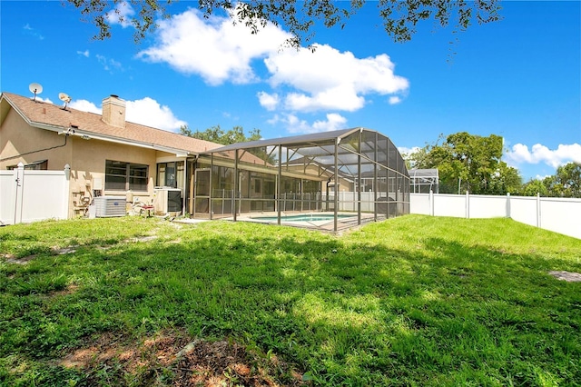 rear view of house with a fenced in pool and a yard