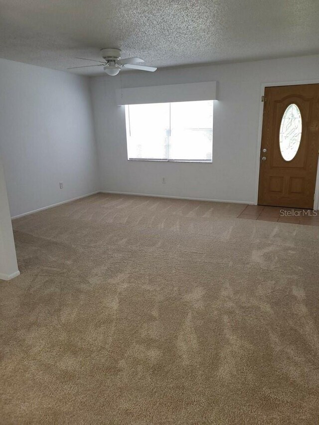 carpeted entrance foyer with ceiling fan and a textured ceiling