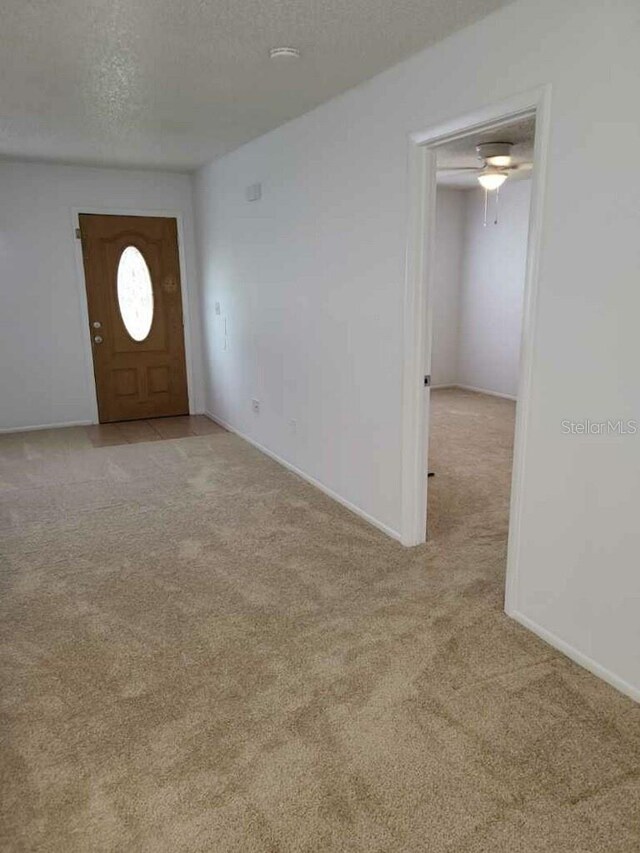 entryway with light carpet and a textured ceiling