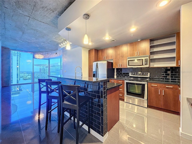 kitchen with decorative light fixtures, a breakfast bar, decorative backsplash, sink, and stainless steel appliances