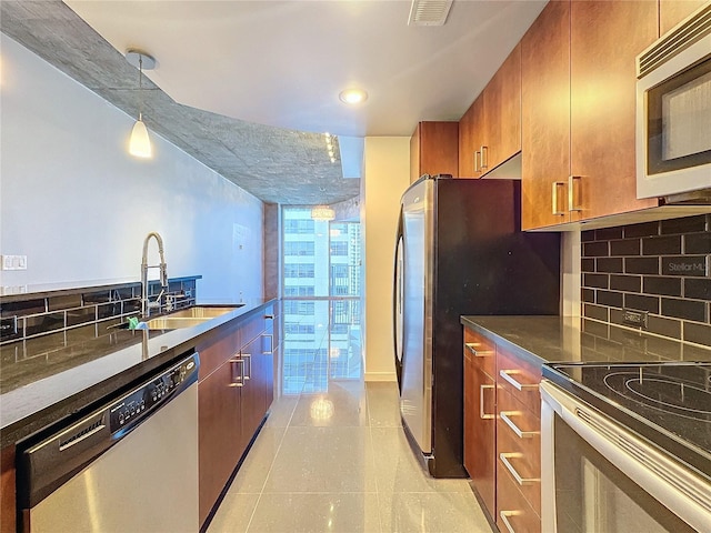 kitchen featuring stainless steel appliances, a wall of windows, backsplash, decorative light fixtures, and sink