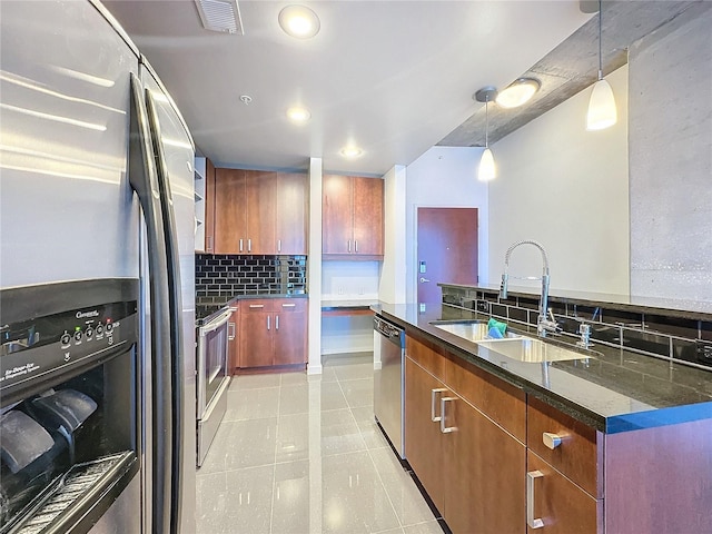 kitchen featuring appliances with stainless steel finishes, decorative backsplash, decorative light fixtures, dark stone counters, and sink