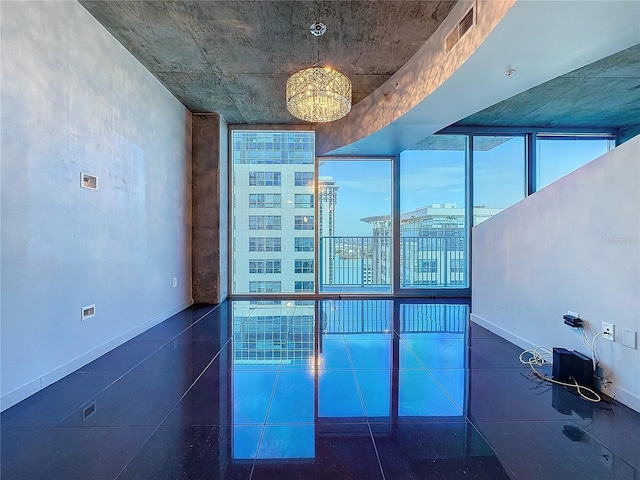 unfurnished room with a wall of windows and a notable chandelier