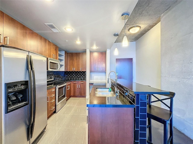 155 S Court Ave Unit 1610, Orlando, FL 32801 - kitchen featuring stainless steel appliances, dark countertops, backsplash, brown cabinets, and a kitchen island with sink
