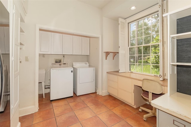 laundry room with light tile patterned floors, washer and clothes dryer, cabinets, and a healthy amount of sunlight