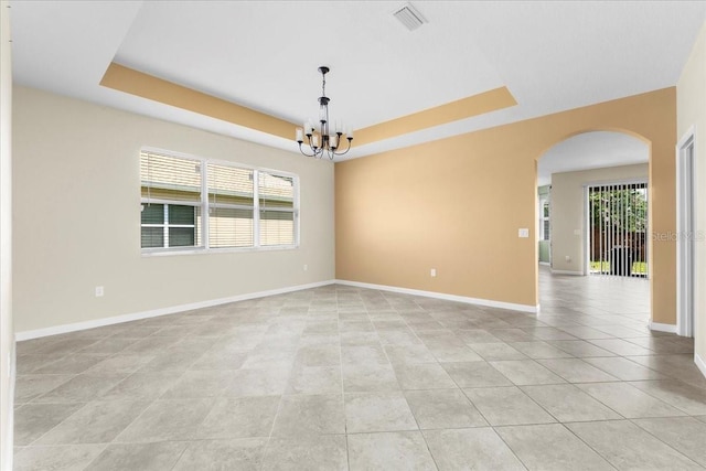 tiled spare room featuring a notable chandelier, plenty of natural light, and a raised ceiling