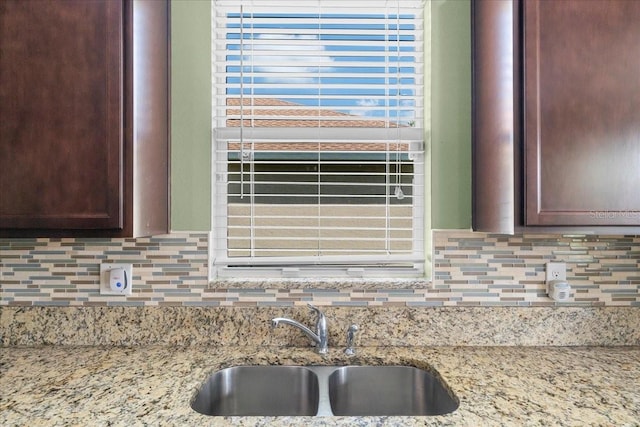 kitchen featuring light stone countertops, sink, and decorative backsplash