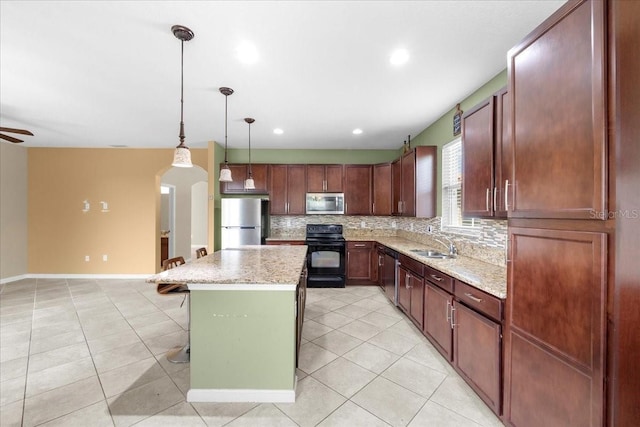 kitchen featuring pendant lighting, sink, appliances with stainless steel finishes, a center island, and light stone counters