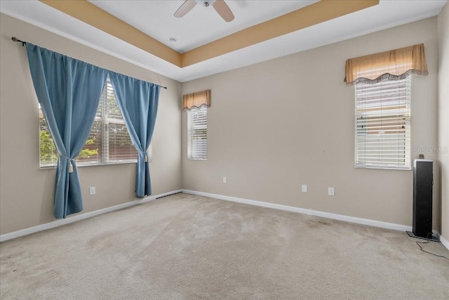 carpeted spare room featuring ceiling fan and a tray ceiling