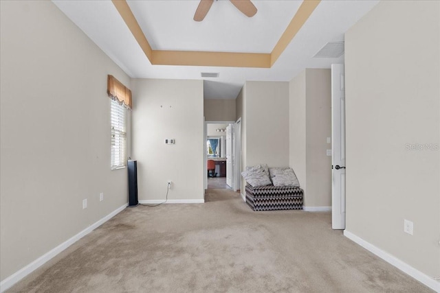 carpeted spare room featuring a raised ceiling and ceiling fan