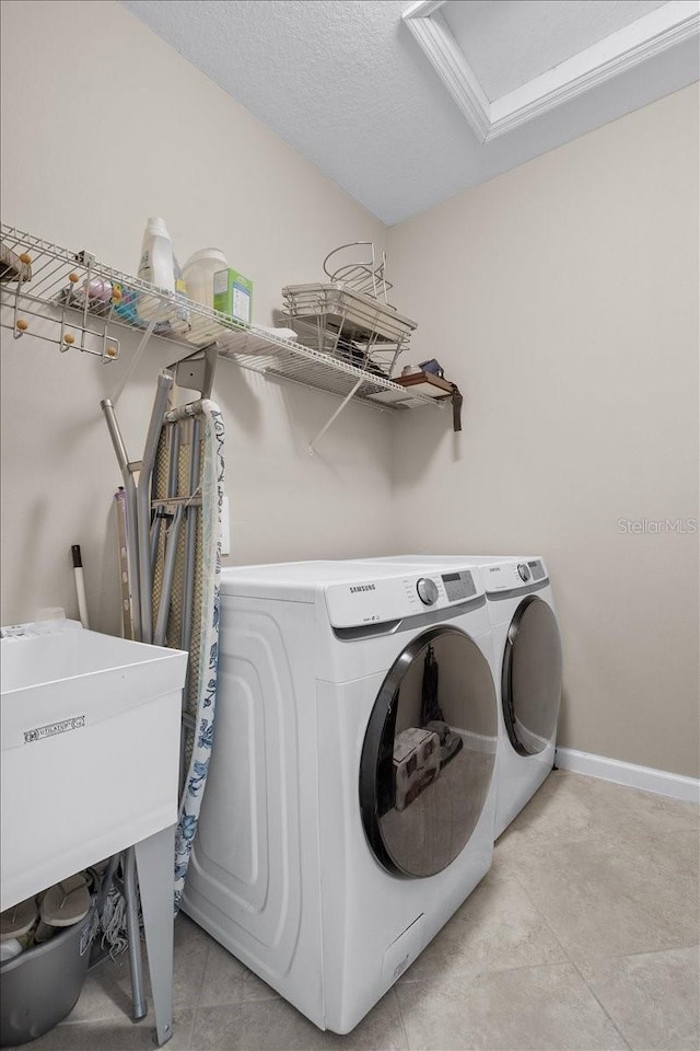 laundry room featuring light tile patterned flooring, washer and dryer, and a textured ceiling