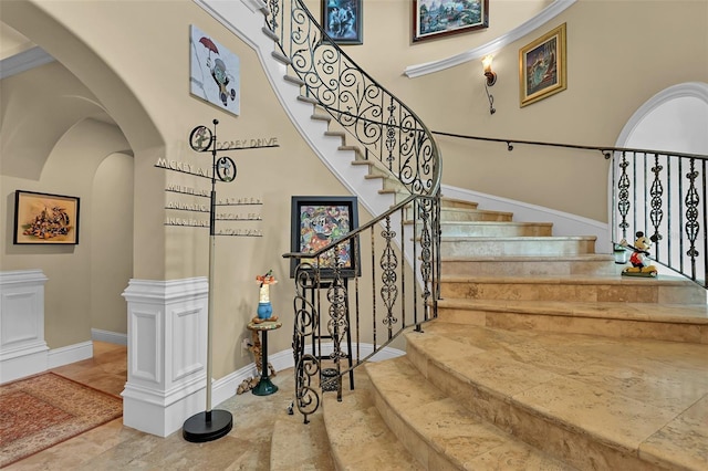 stairs featuring baseboards, arched walkways, and a towering ceiling