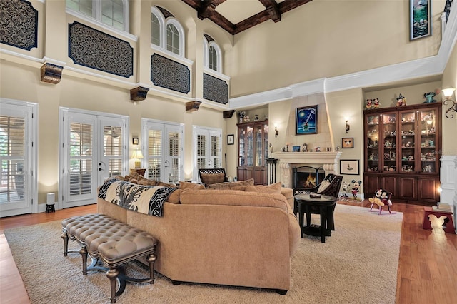 living room featuring french doors, a towering ceiling, beamed ceiling, and hardwood / wood-style flooring