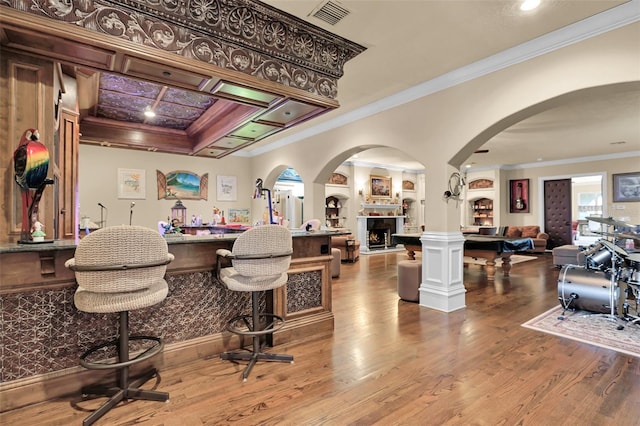 bar featuring crown molding, wood finished floors, visible vents, and a warm lit fireplace