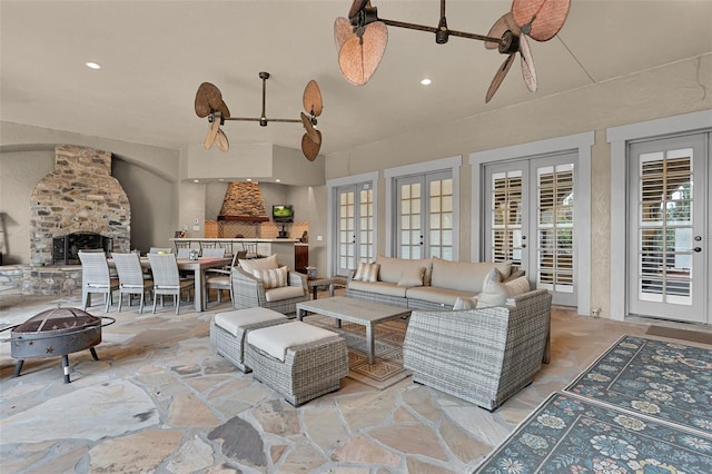 living room featuring ceiling fan, french doors, and a stone fireplace