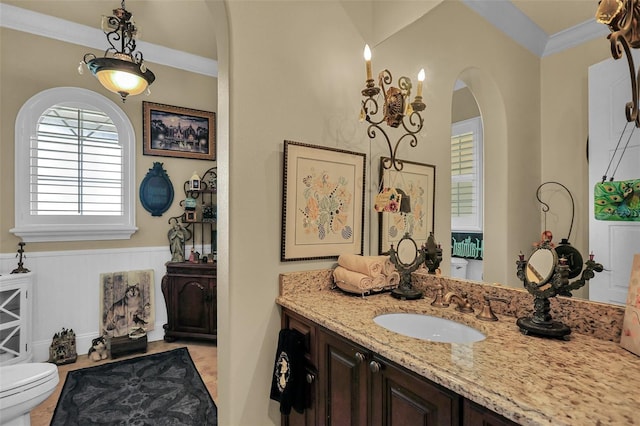 bathroom featuring vanity, toilet, wainscoting, and ornamental molding