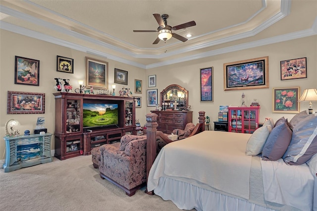 carpeted bedroom with ceiling fan, a tray ceiling, and ornamental molding