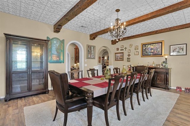 dining space featuring a notable chandelier, beamed ceiling, and hardwood / wood-style floors