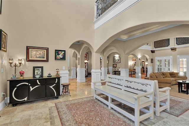 living room featuring arched walkways, a towering ceiling, and a decorative wall