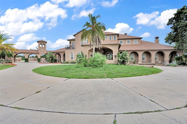 mediterranean / spanish house featuring concrete driveway, a front lawn, and stucco siding