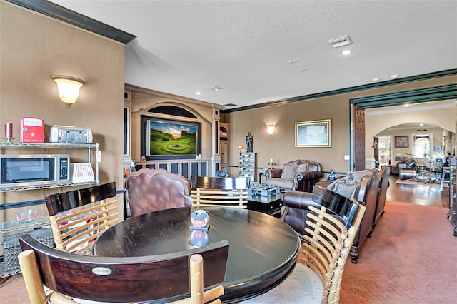 carpeted dining room featuring ornamental molding and a textured ceiling