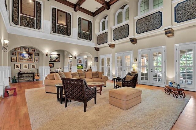 living room featuring beam ceiling, a towering ceiling, french doors, and decorative columns