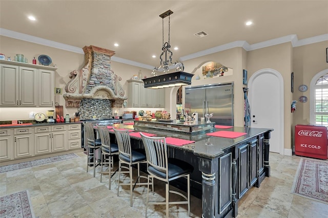 kitchen with a kitchen island, dark stone counters, stainless steel appliances, wall chimney exhaust hood, and cream cabinets