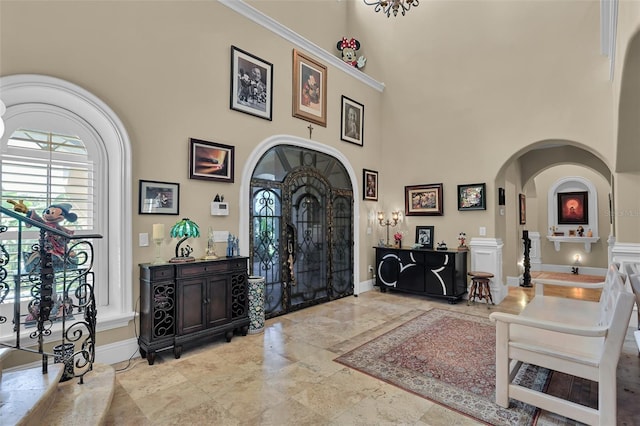 entrance foyer featuring baseboards, arched walkways, and a towering ceiling