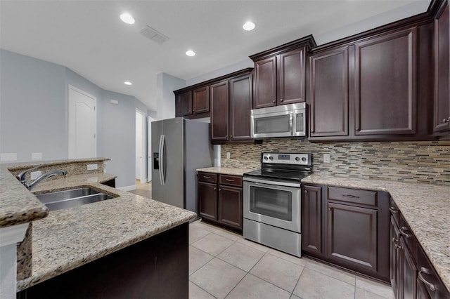 kitchen with sink, appliances with stainless steel finishes, backsplash, light stone counters, and light tile patterned flooring