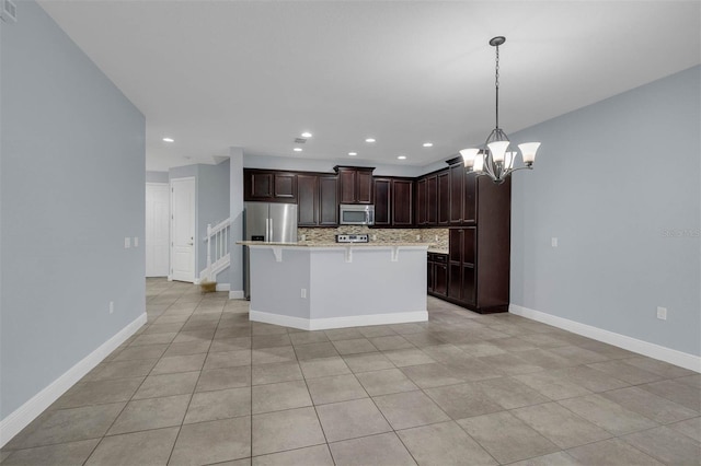 kitchen featuring appliances with stainless steel finishes, backsplash, a kitchen breakfast bar, a center island, and decorative light fixtures