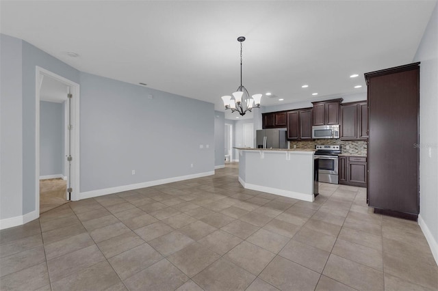 kitchen featuring appliances with stainless steel finishes, pendant lighting, an island with sink, backsplash, and dark brown cabinetry