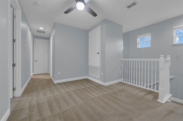 empty room featuring ceiling fan and light carpet