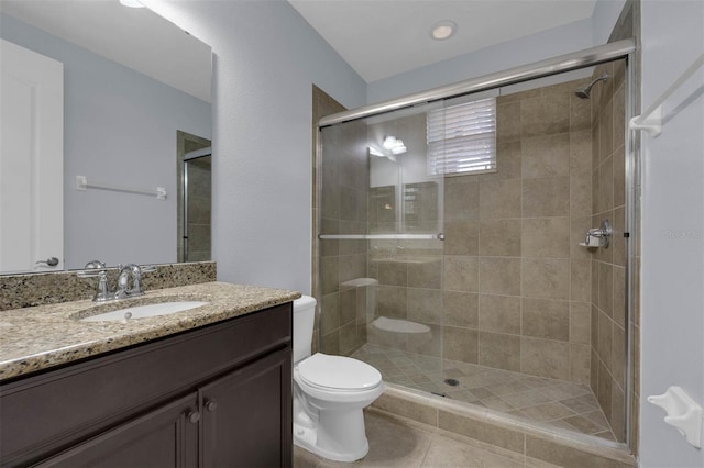 bathroom featuring tile patterned floors, vanity, toilet, and a shower with shower door