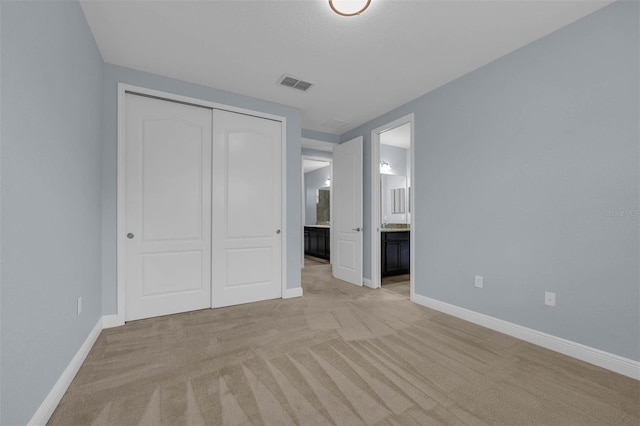 unfurnished bedroom featuring connected bathroom, light colored carpet, and a closet