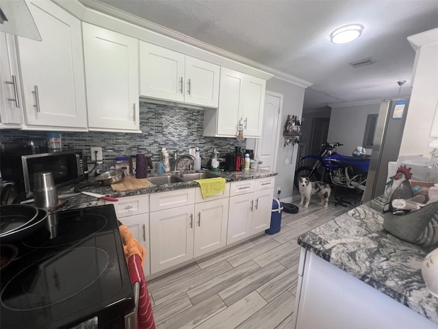 kitchen with white cabinets, dark stone countertops, crown molding, and decorative backsplash