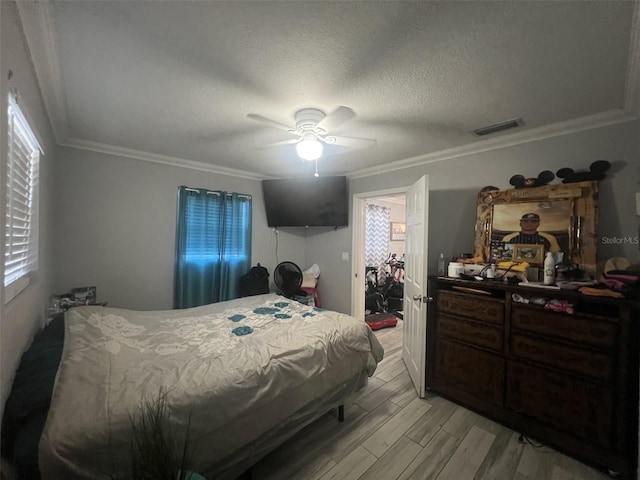 bedroom with ornamental molding, light hardwood / wood-style flooring, a textured ceiling, and ceiling fan