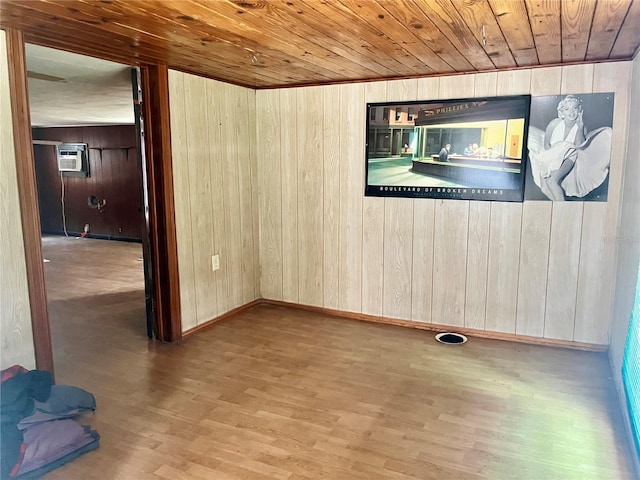 spare room with a wall mounted AC, wood ceiling, hardwood / wood-style floors, and wooden walls