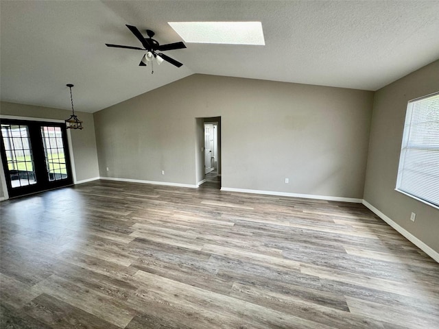 spare room with lofted ceiling with skylight, a textured ceiling, baseboards, and dark wood-type flooring