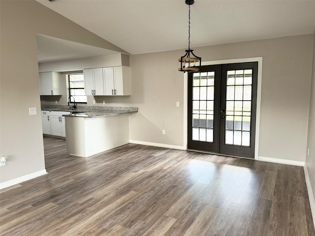 kitchen featuring a peninsula, dark wood-type flooring, a sink, and white cabinetry