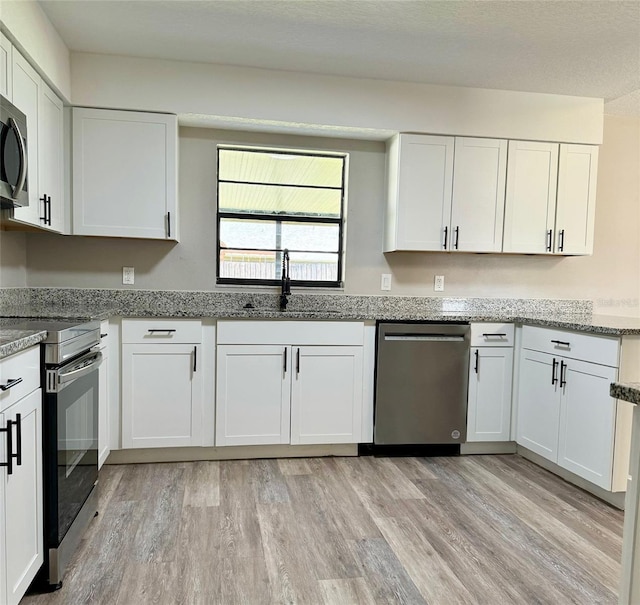 kitchen featuring white cabinetry, light wood-type flooring, and stainless steel appliances