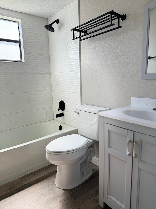 full bathroom with a textured ceiling, toilet, tiled shower / bath combo, vanity, and wood-type flooring