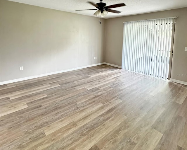 spare room featuring ceiling fan, a textured ceiling, baseboards, and wood finished floors