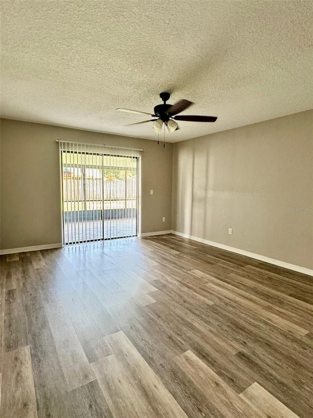 empty room with wood finished floors, a ceiling fan, and baseboards