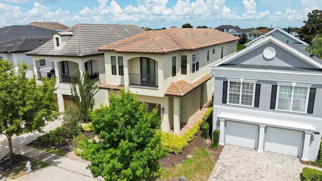 view of front of home featuring decorative driveway, stucco siding, a garage, a residential view, and a tiled roof