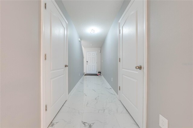 corridor with light tile patterned floors and a textured ceiling