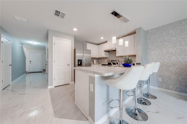 kitchen featuring a breakfast bar area, white cabinets, decorative light fixtures, light tile patterned floors, and stainless steel refrigerator with ice dispenser