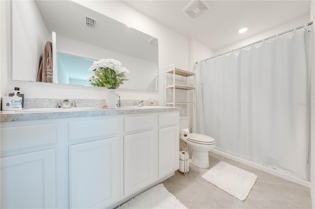 bathroom featuring toilet, tile patterned floors, and double sink vanity